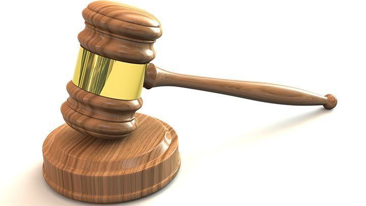 Wooden gavel on a wooden block; gold band on gavel's head.