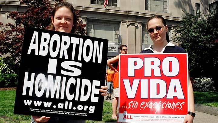 Two people hold signs: