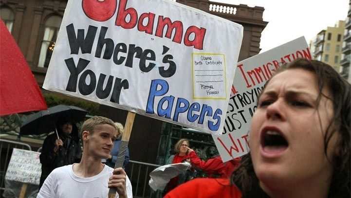 Protesters holding signs with text, one saying
