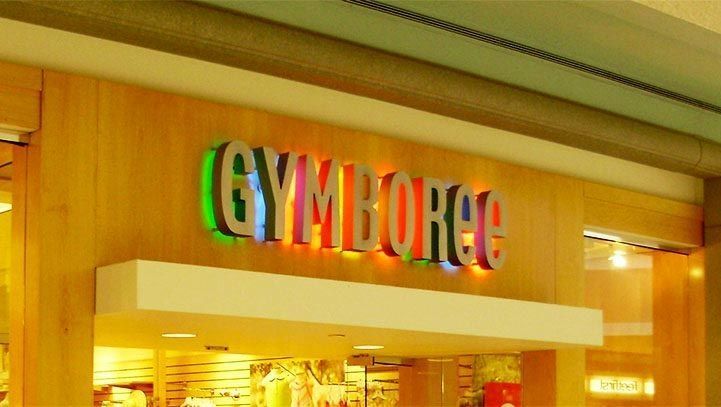 Gymboee store sign at a mall entrance; colorful logo against a light-colored wooden wall.