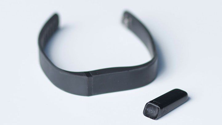 Black fitness tracker with detached sensor on a white surface.