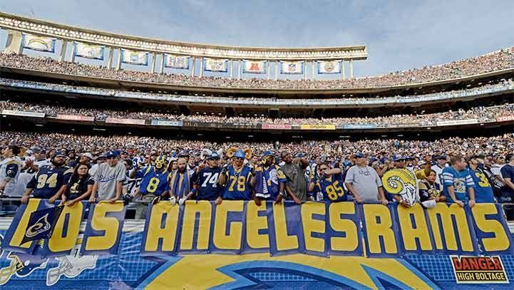 Fans in blue and gold jerseys hold a banner reading