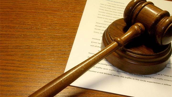 Wooden gavel on a wooden sound block resting on top of a document.