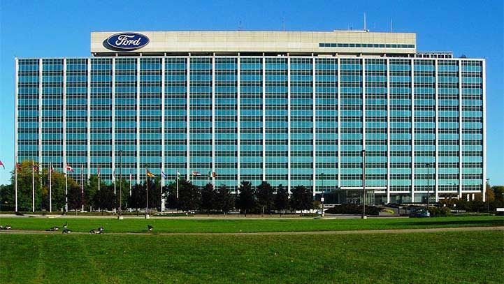 Ford World Headquarters, a large, rectangular, glass-walled office building, with the Ford logo on top.