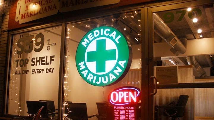 A medical marijuana dispensary at night with an illuminated sign and an