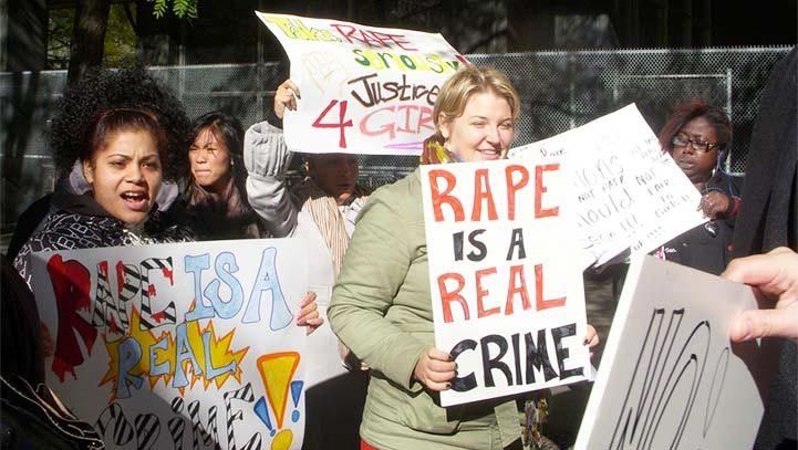 People holding signs protesting rape; some signs read