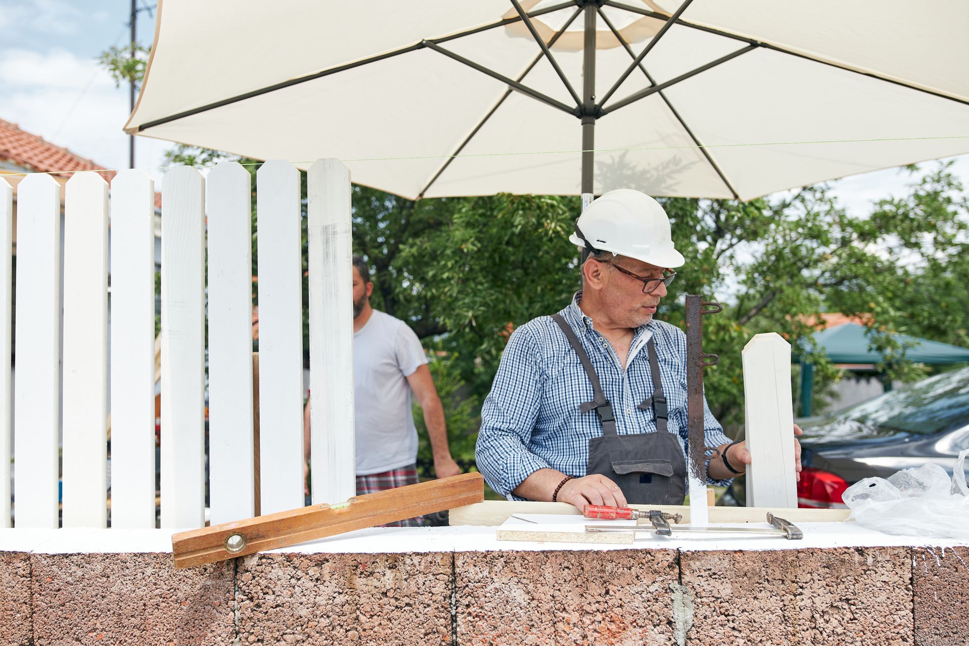 An old man working on a wooden fence, showcasing expert craftsmanship by local fence contractors.