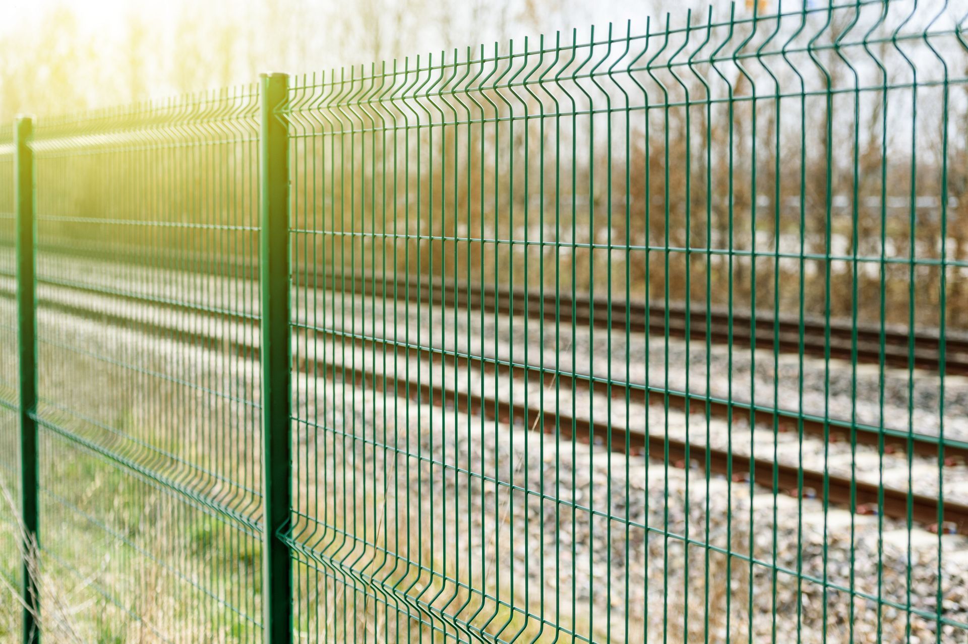 A metallic green fence is illuminated by the sun with a blurry background. A metallic green fence is illuminated by the sun with a blurry background.