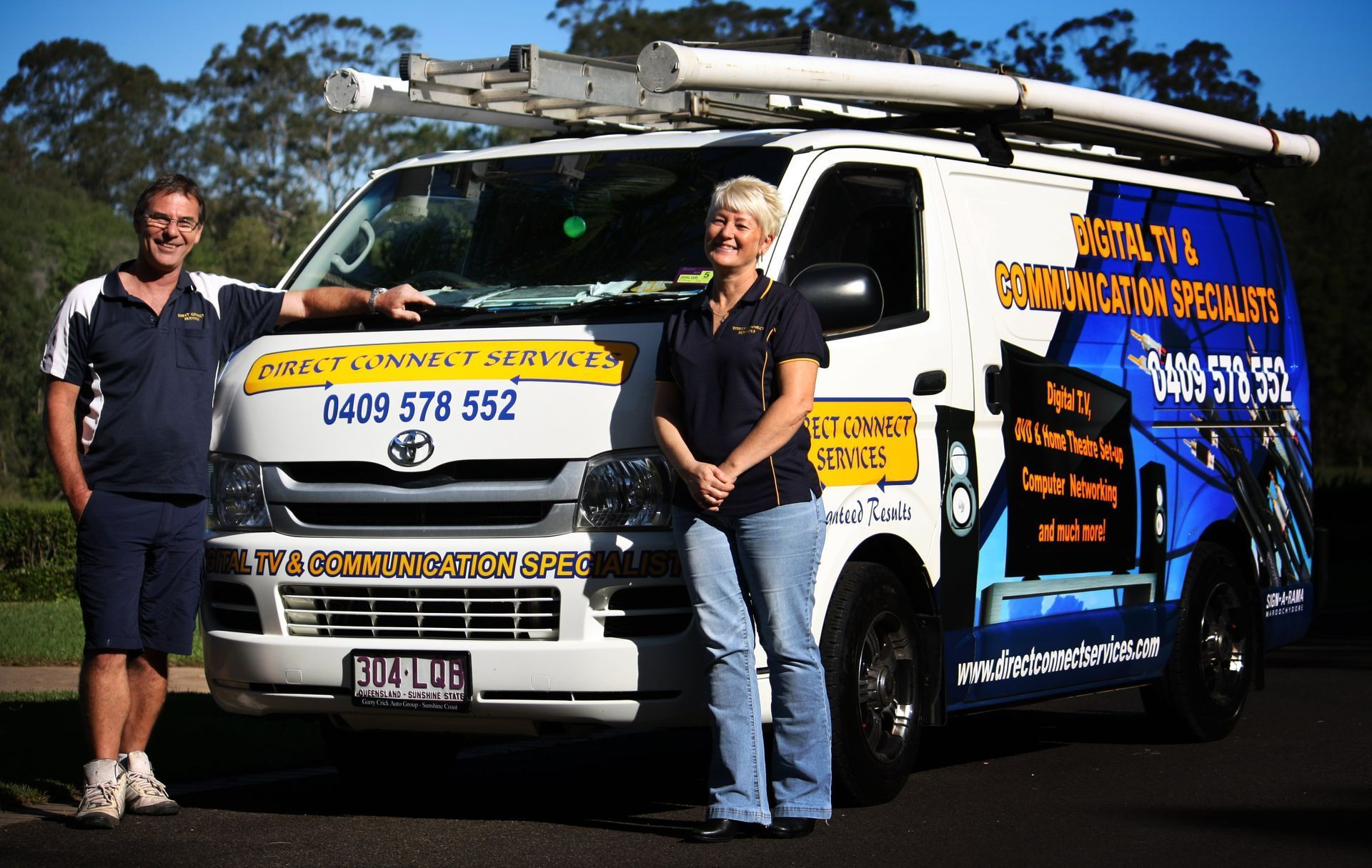 A man and a woman standing infront of a work vehicle