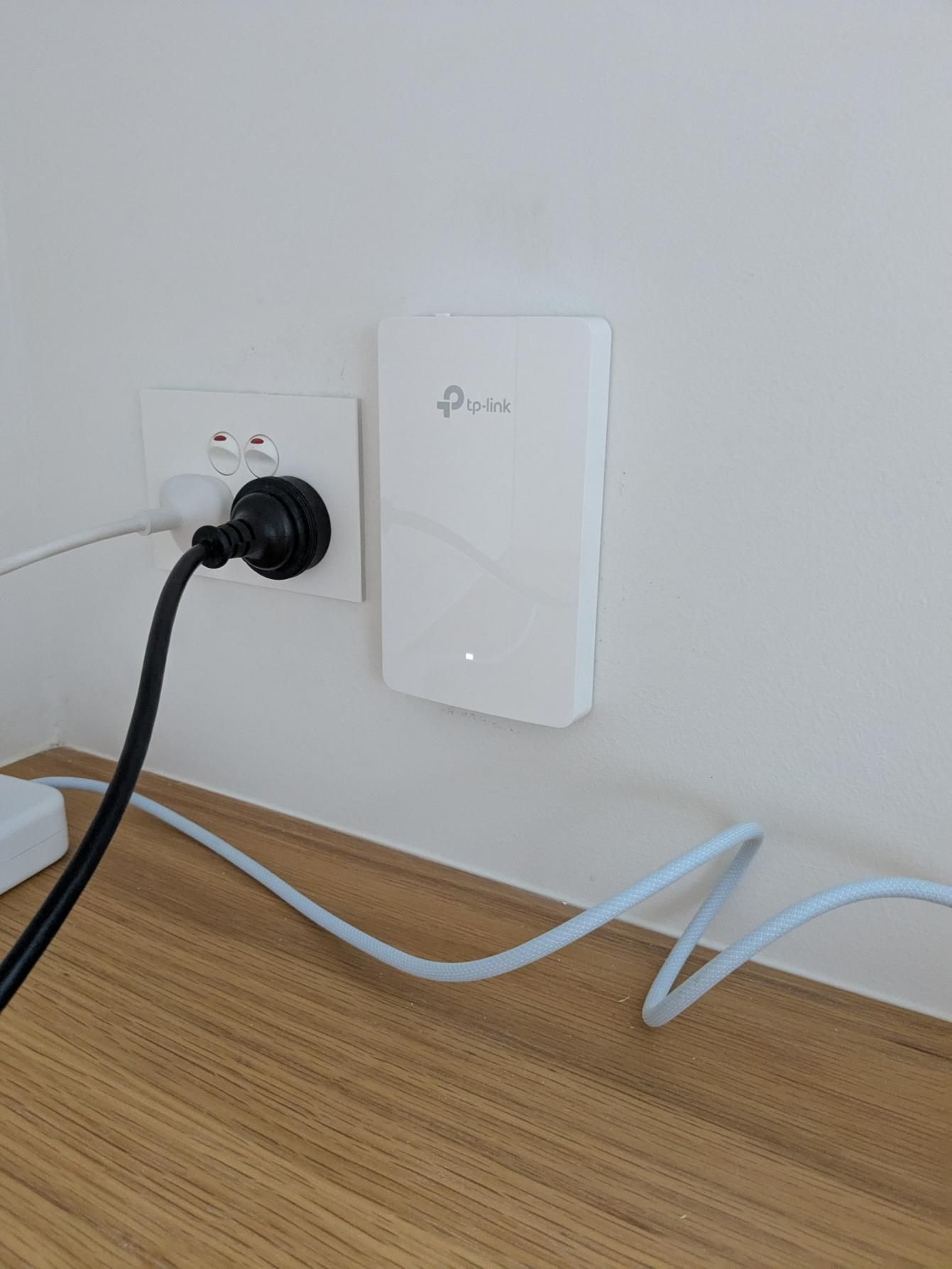 A Tp Link Router is Plugged Into a Wall Socket on a Wooden Desk — Direct Connect Services In Woombye, QLD