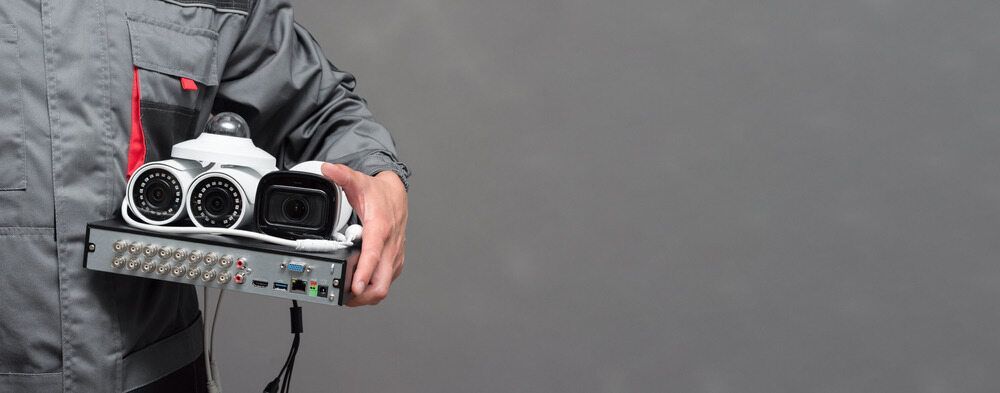 A Man is Holding a Box of Security Cameras in His Hands — Direct Connect Services In Caloundra, QLD
