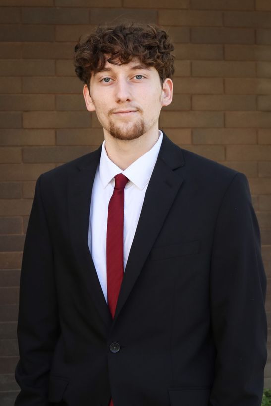 A living room with a couch and a wooden table with a vase of flowers on it.
