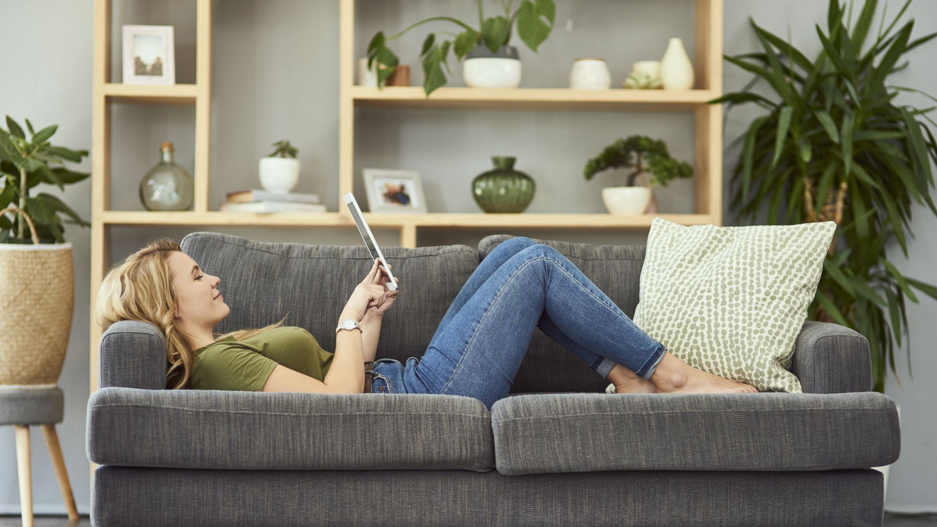 Woman layout on a couch looking at her laptop