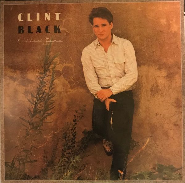 Clint Black leans against a textured wall, wearing a button-down shirt and dark pants. The album cover is for his debut album,