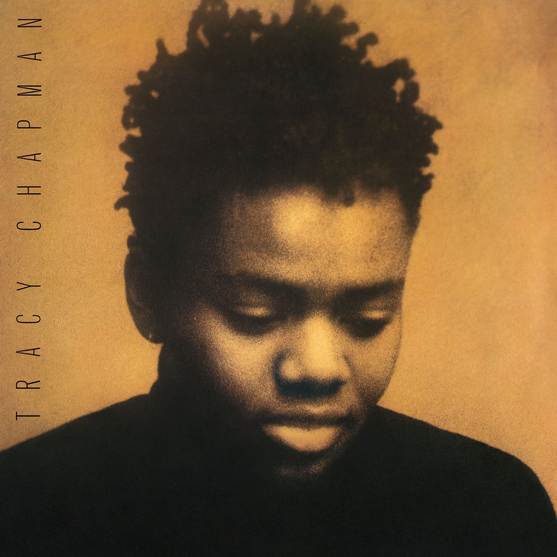 Album cover of Tracy Chapman, close-up photo of her face, looking down with a pensive expression, set against a warm background.