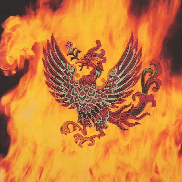 Stylized phoenix with outstretched wings holding a sprig in its beak, set against a backdrop of bright orange flames.