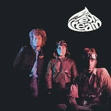 Cream band members pose on a black background, lit by red and blue lights, with the