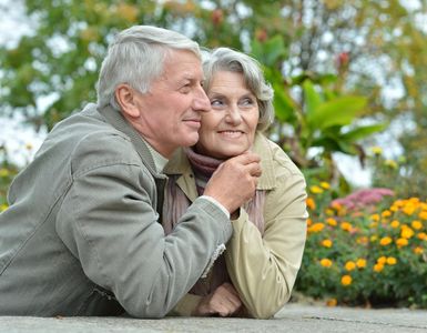 Two people resting together in a garden, with flowers and greenery in the background.