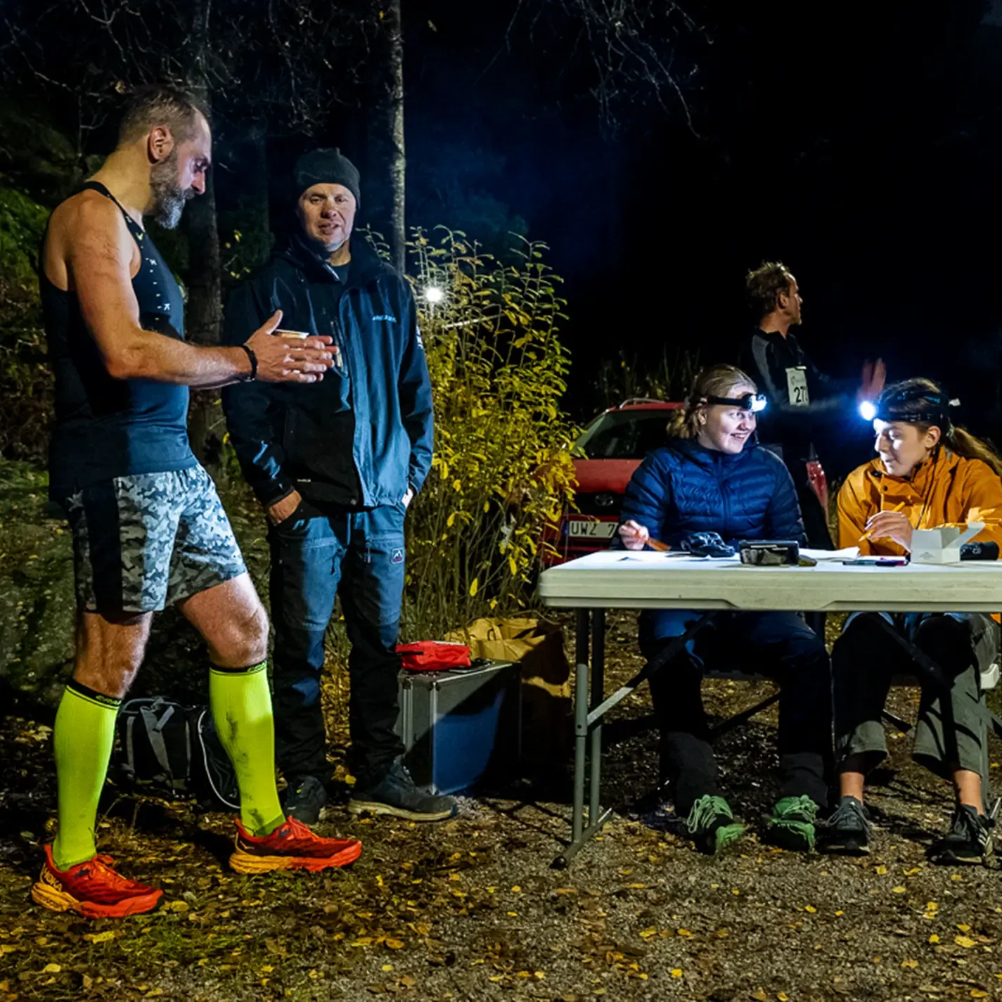 A group of people are standing around a table at night
