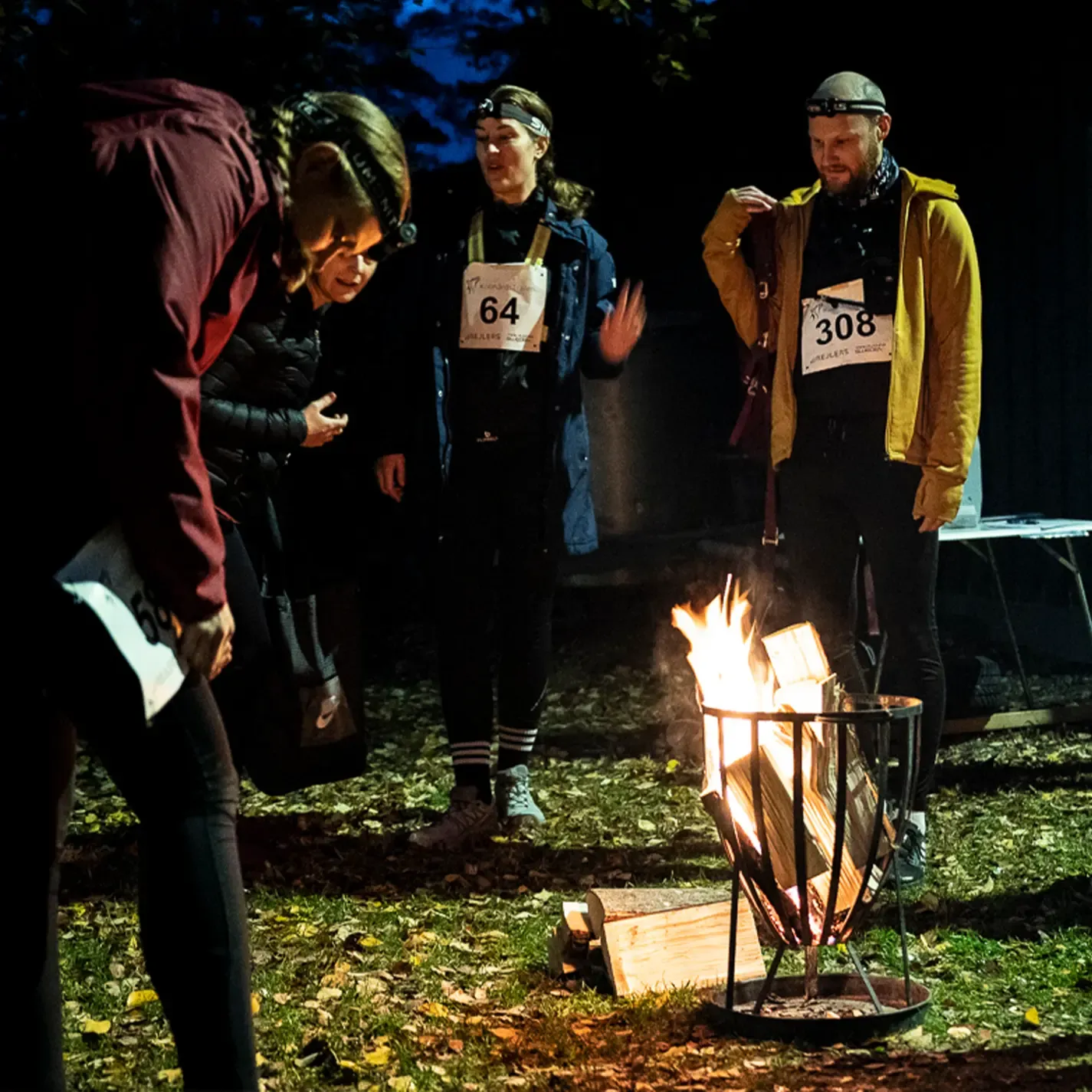 A group of people standing around a fire with one wearing the number 308