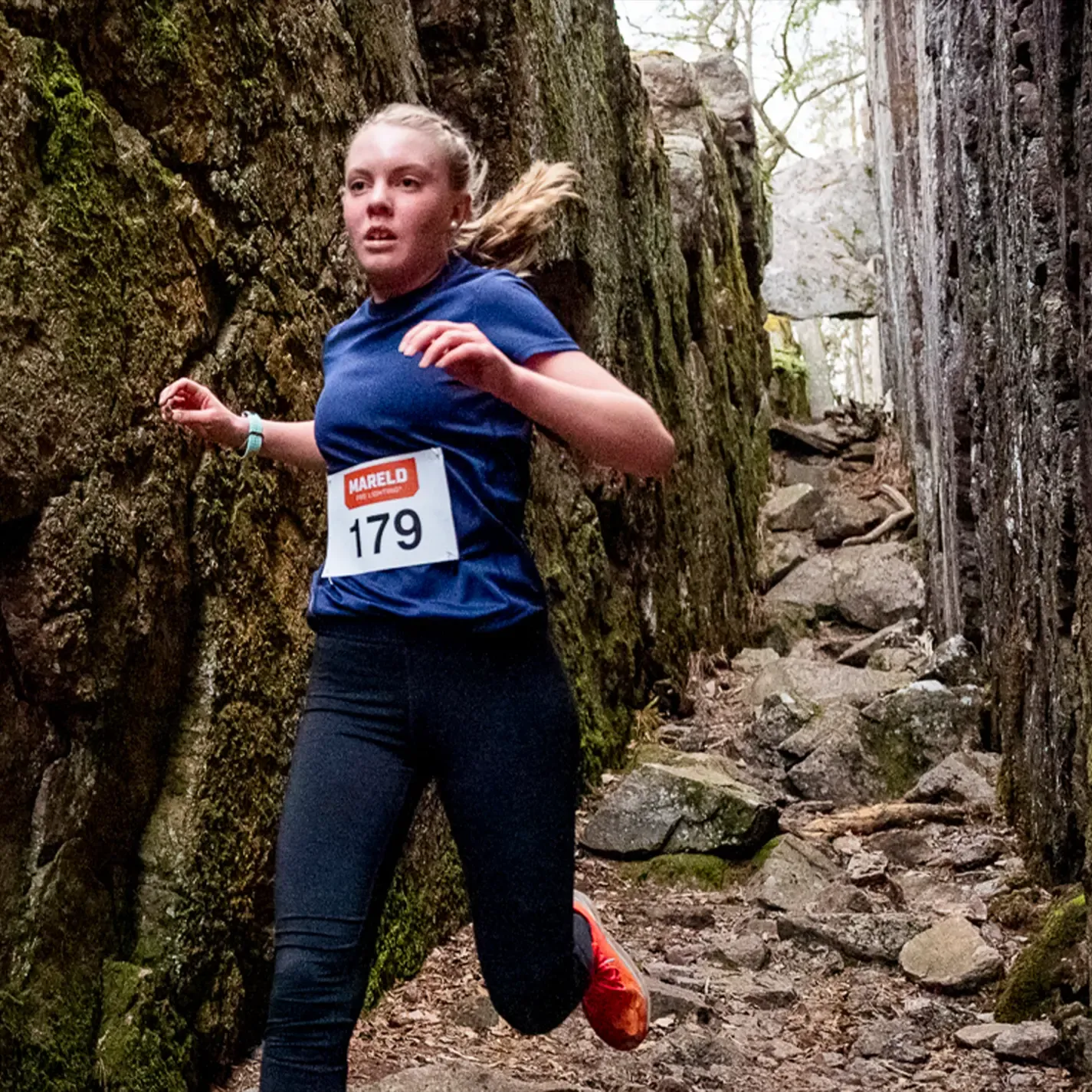 A woman is running in a race with the number 179 on her shirt.