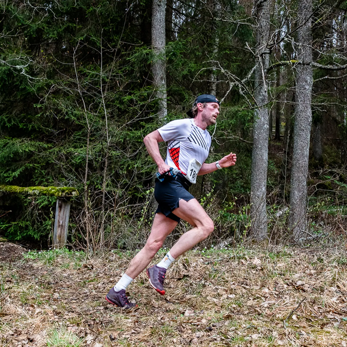 A man is running on a trail in the woods.