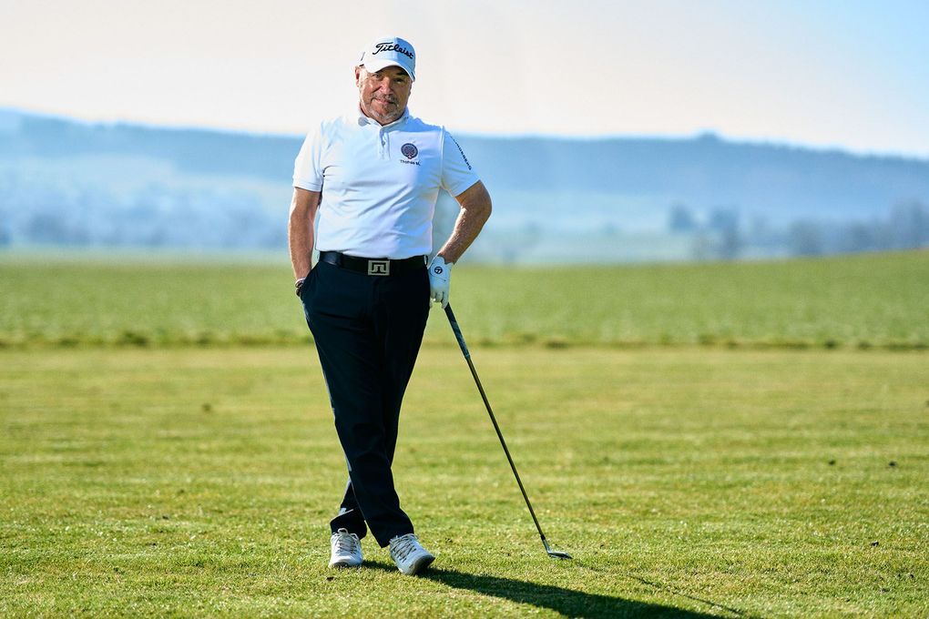 Thomas Mondani im weißen Shirt steht auf einem grünen Fairway und hält einen Schläger unter klarem blauen Himmel
