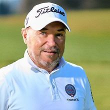 Thomas Mondani weißer Titleist-Kappe und -Shirt steht auf einem grünen Golfplatz und lächelt in die Kamera.