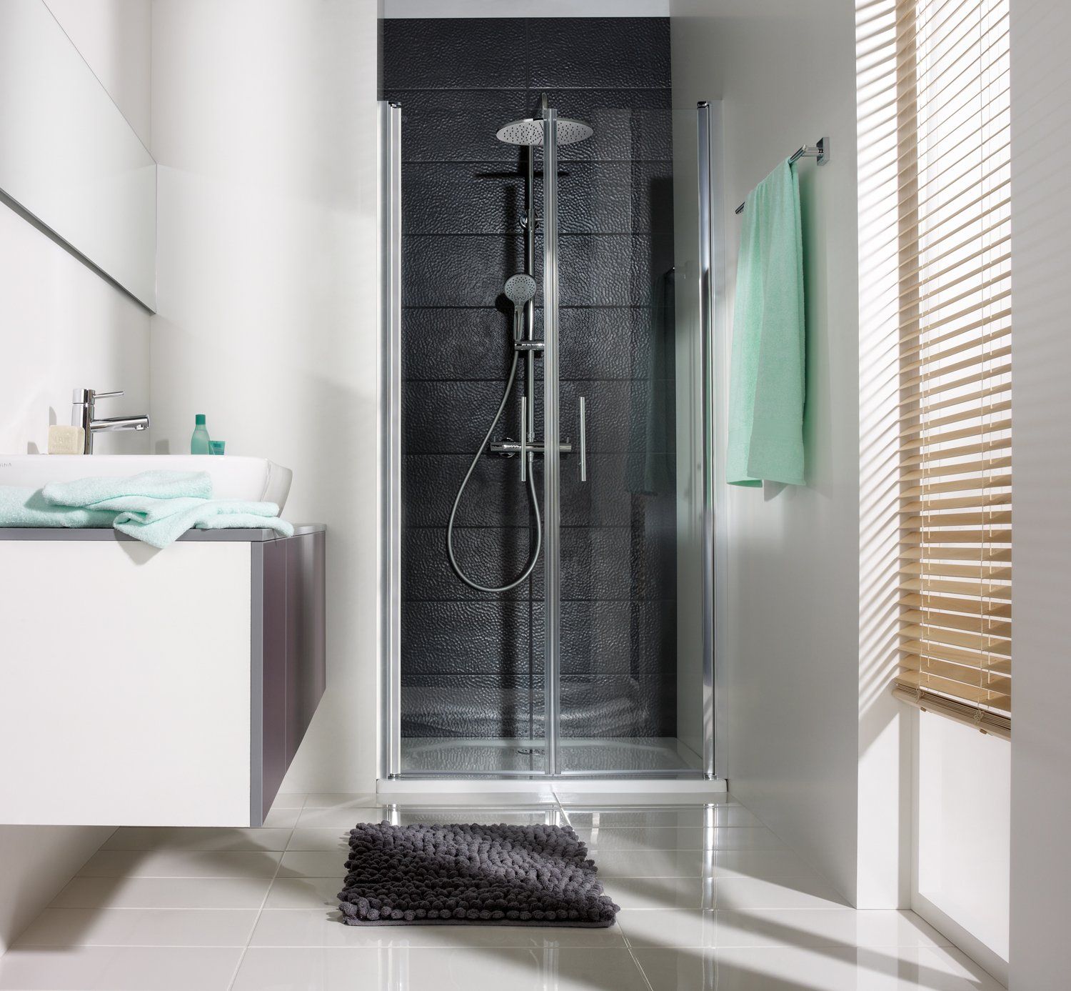 Dusche in Nischemit schwarzen Wandfliesen in kleinem Bad mit großem Fenster