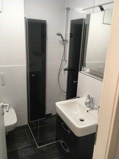 Dusche mit Eckeinstieg mit schwarzweißen Fliesen und geöffneten Türen