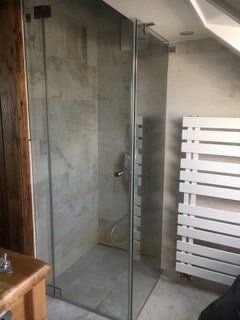 Dusche mit grauen Fliesen neben Handtuchhalter