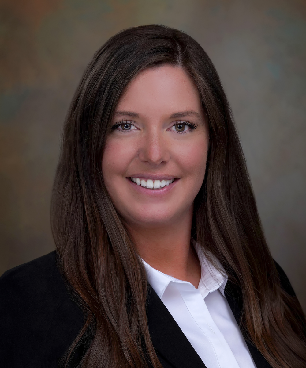 A woman in a black jacket and white shirt is smiling for the camera.