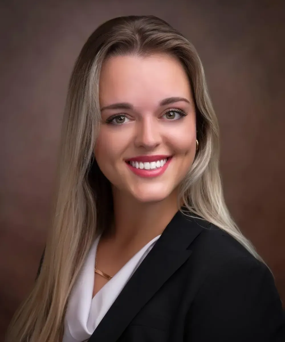 A woman in a black jacket and white shirt is smiling for the camera.