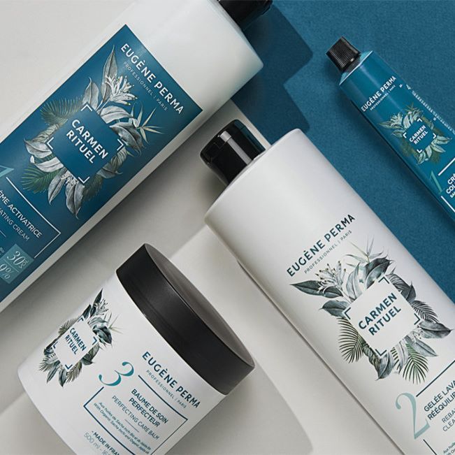 Quatre flacons blancs et un pot de produits capillaires Eugène Perma avec des touches de bleu et d'argent.