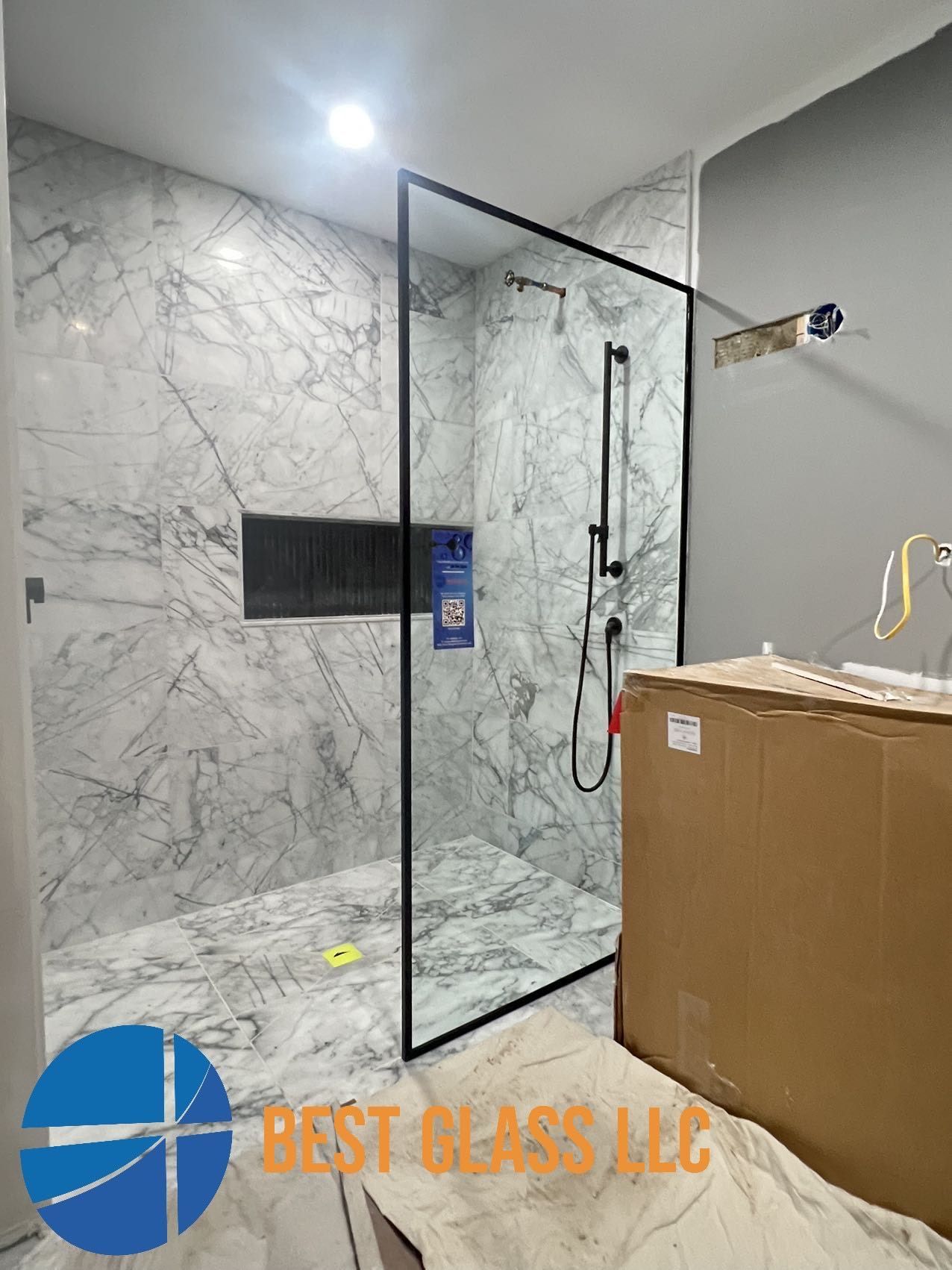 A bathroom with a walk in shower and a box on the floor.