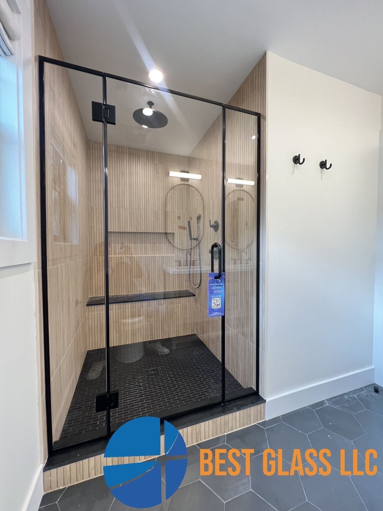 A bathroom with a walk in shower with a black frame.