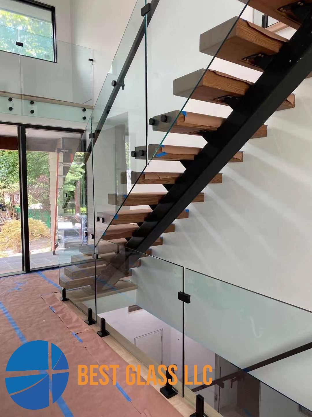 A staircase with a glass railing is being built in a house