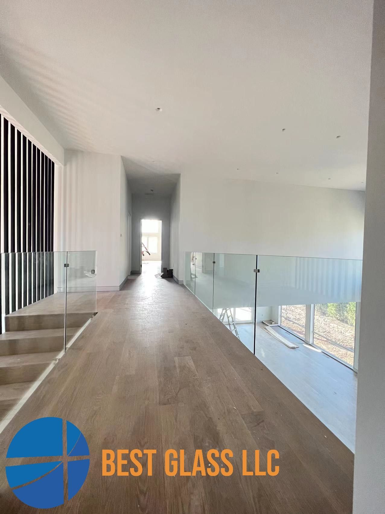 A hallway with a glass railing and stairs in a house.