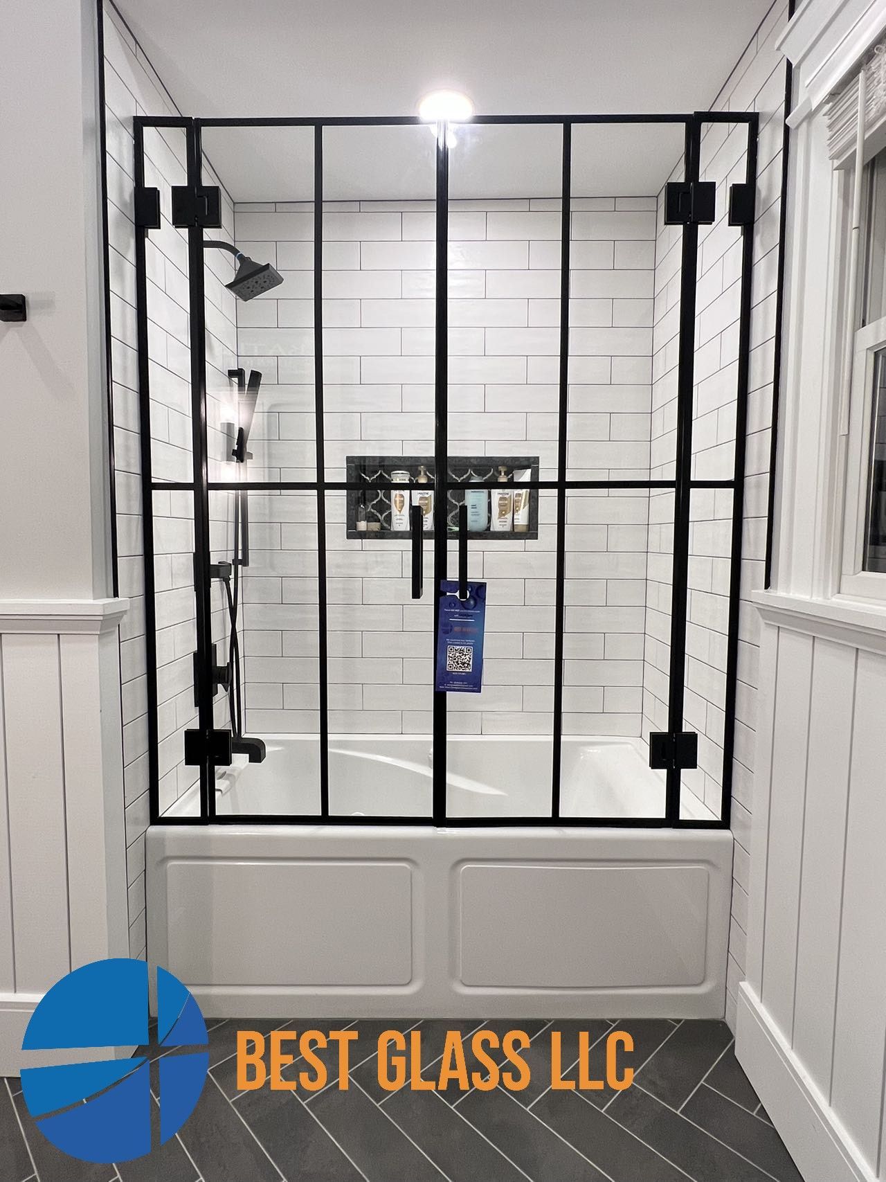 A bathroom with a bathtub and a shower stall with a black frame.