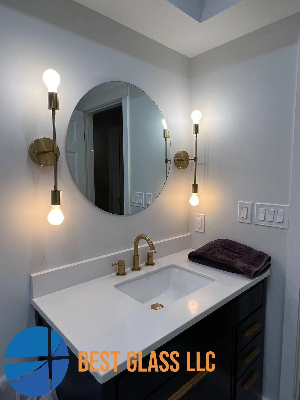 A bathroom with a sink , mirror and two lights.