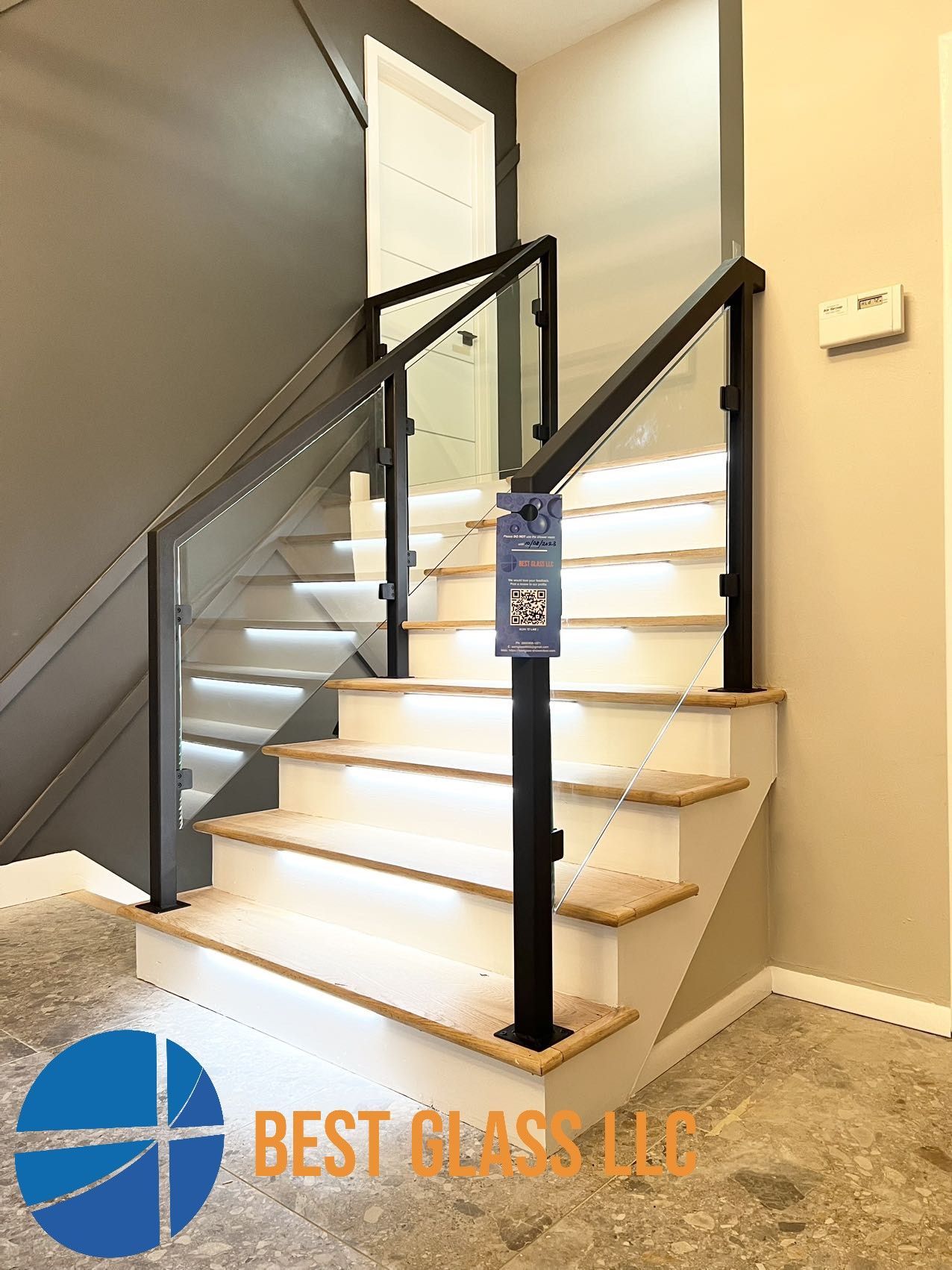 A staircase with a glass railing and lights on the steps.
