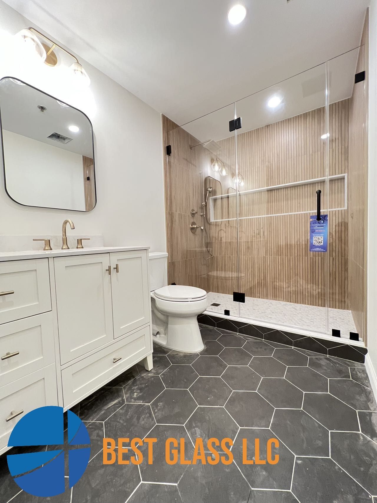 A bathroom with a toilet , sink , mirror and walk in shower.