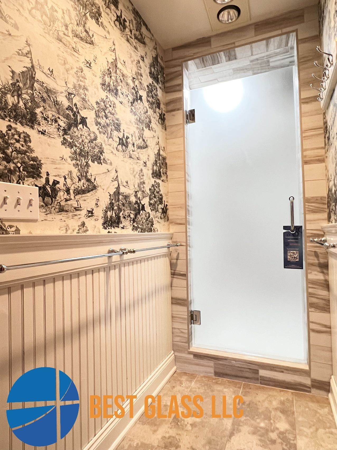 A bathroom with a glass shower door and a painting on the wall.