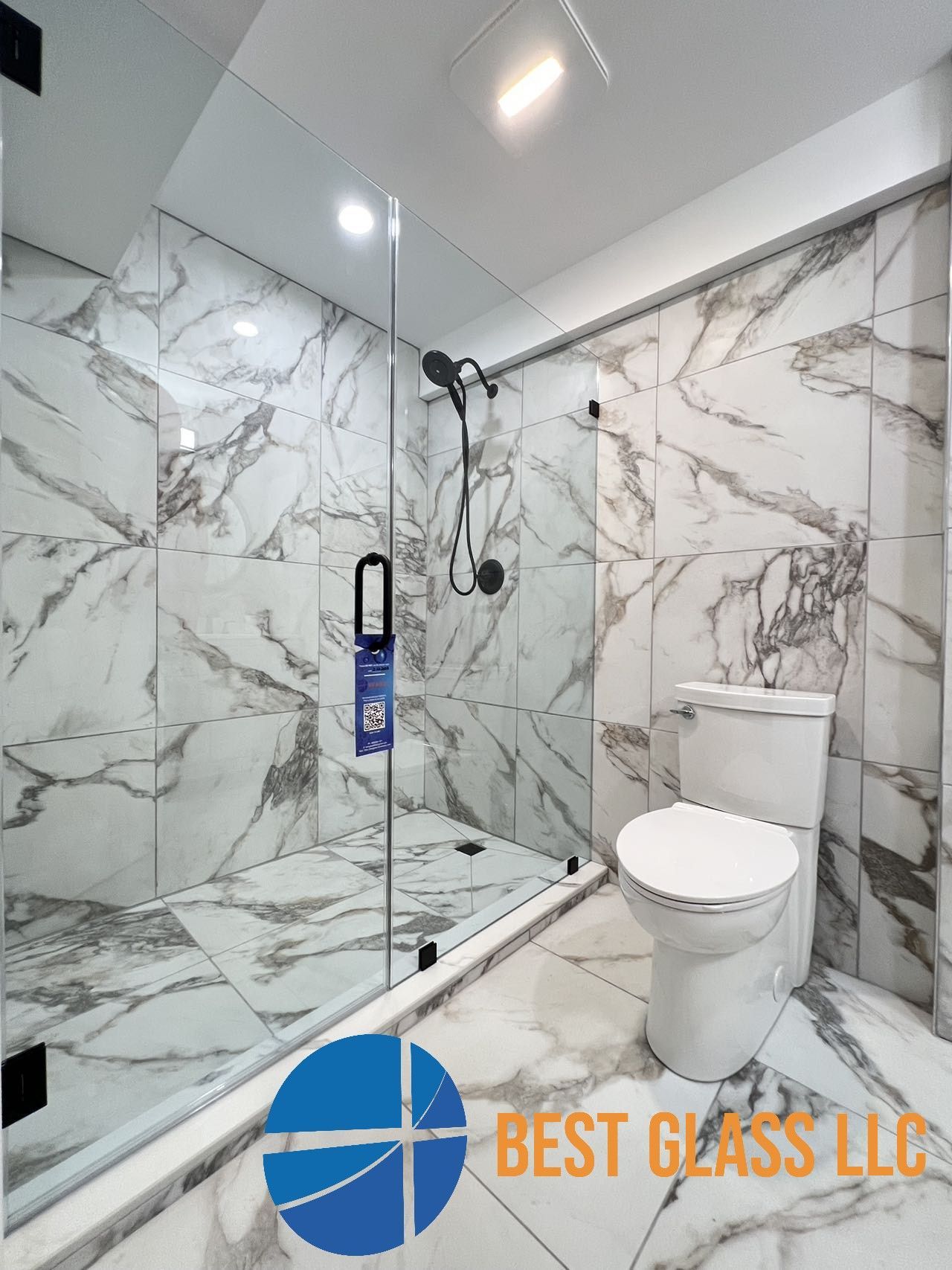 A bathroom with marble tiles , a toilet , and a shower stall.