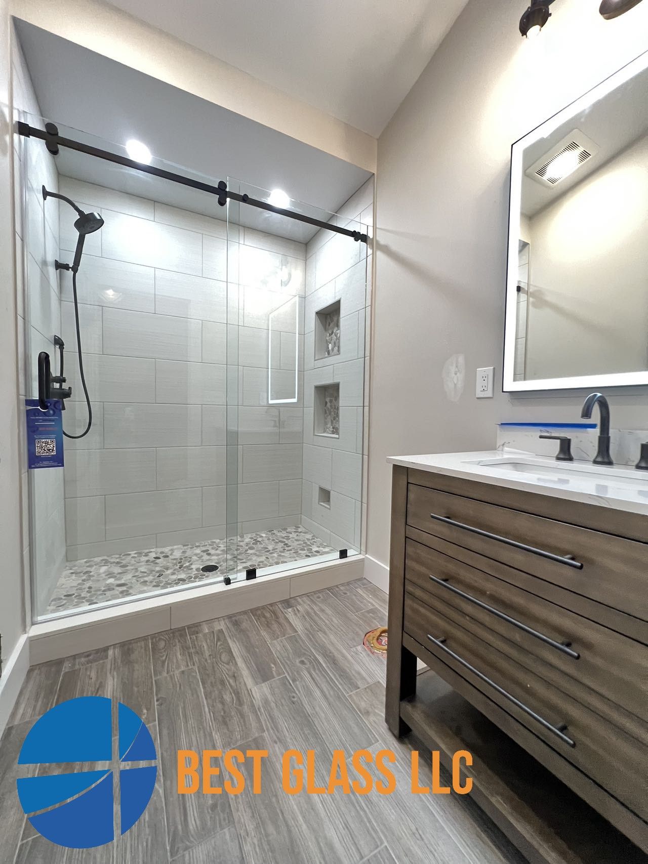 A bathroom with a walk in shower , sink and mirror.
