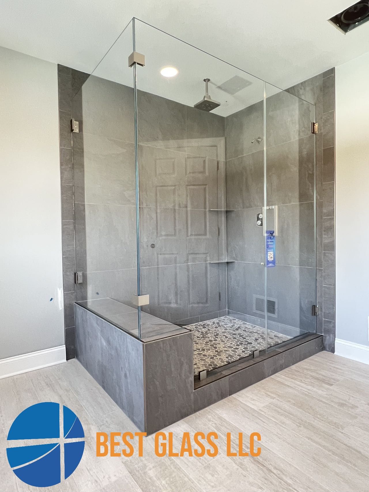 A bathroom with a walk in shower with a glass door.