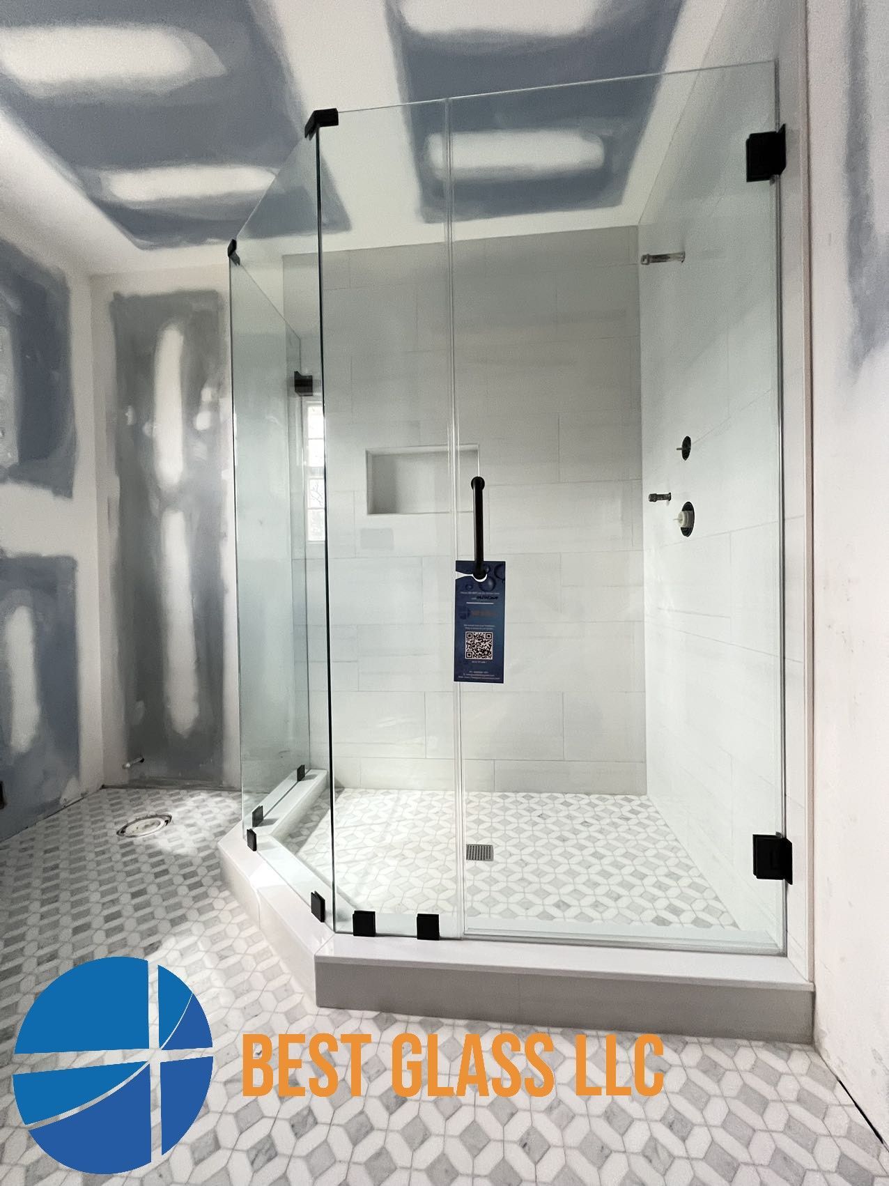 A bathroom with a walk in shower and a sign that says best glass llc