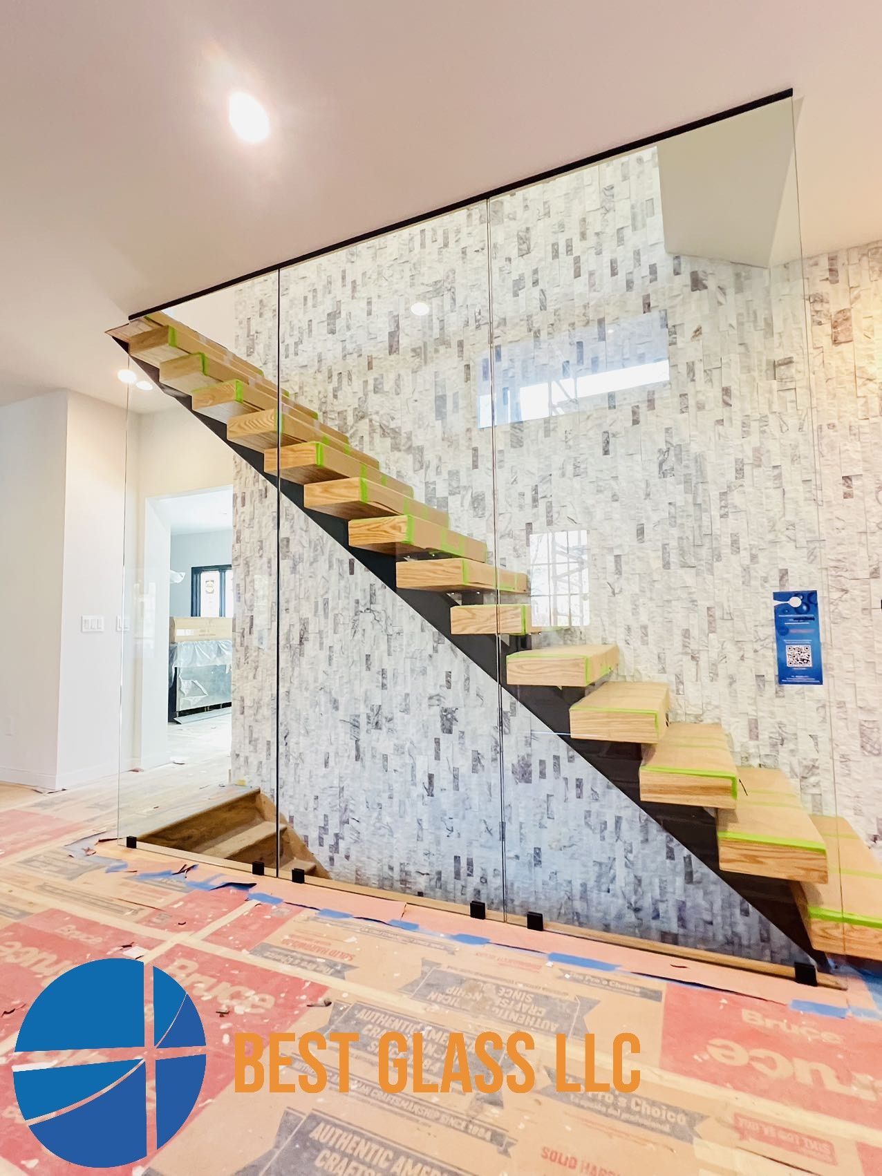 A staircase with a glass railing is being built in a house.
