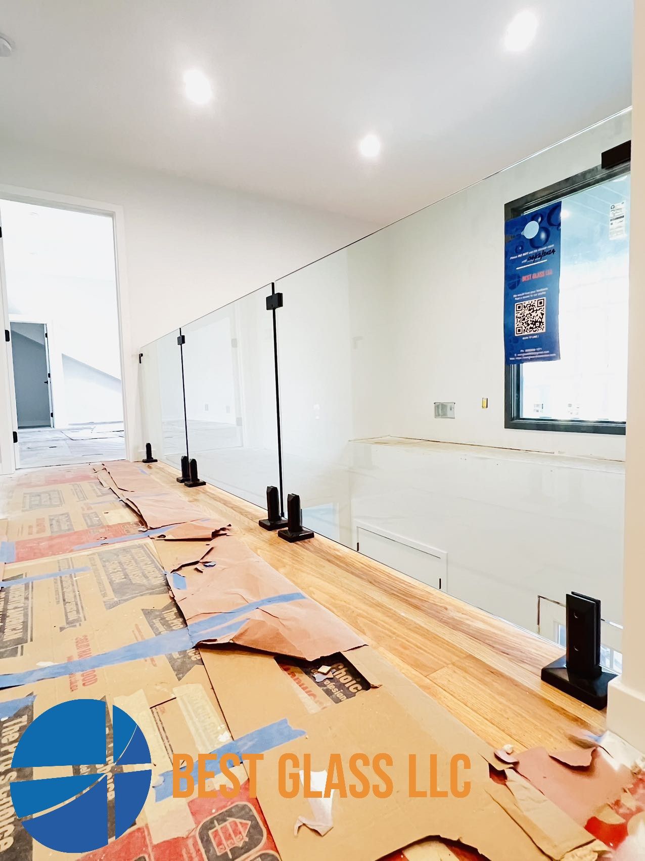 A glass railing is being installed on a wooden floor in a room.