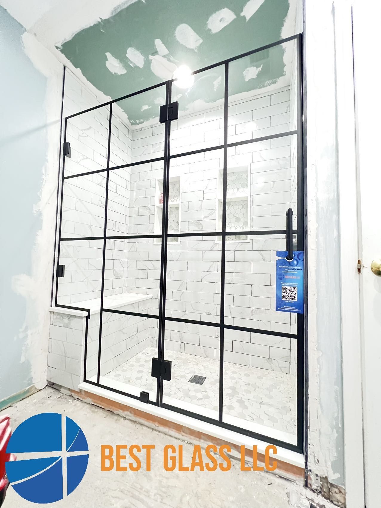 A bathroom with a walk in shower with a black frame.
